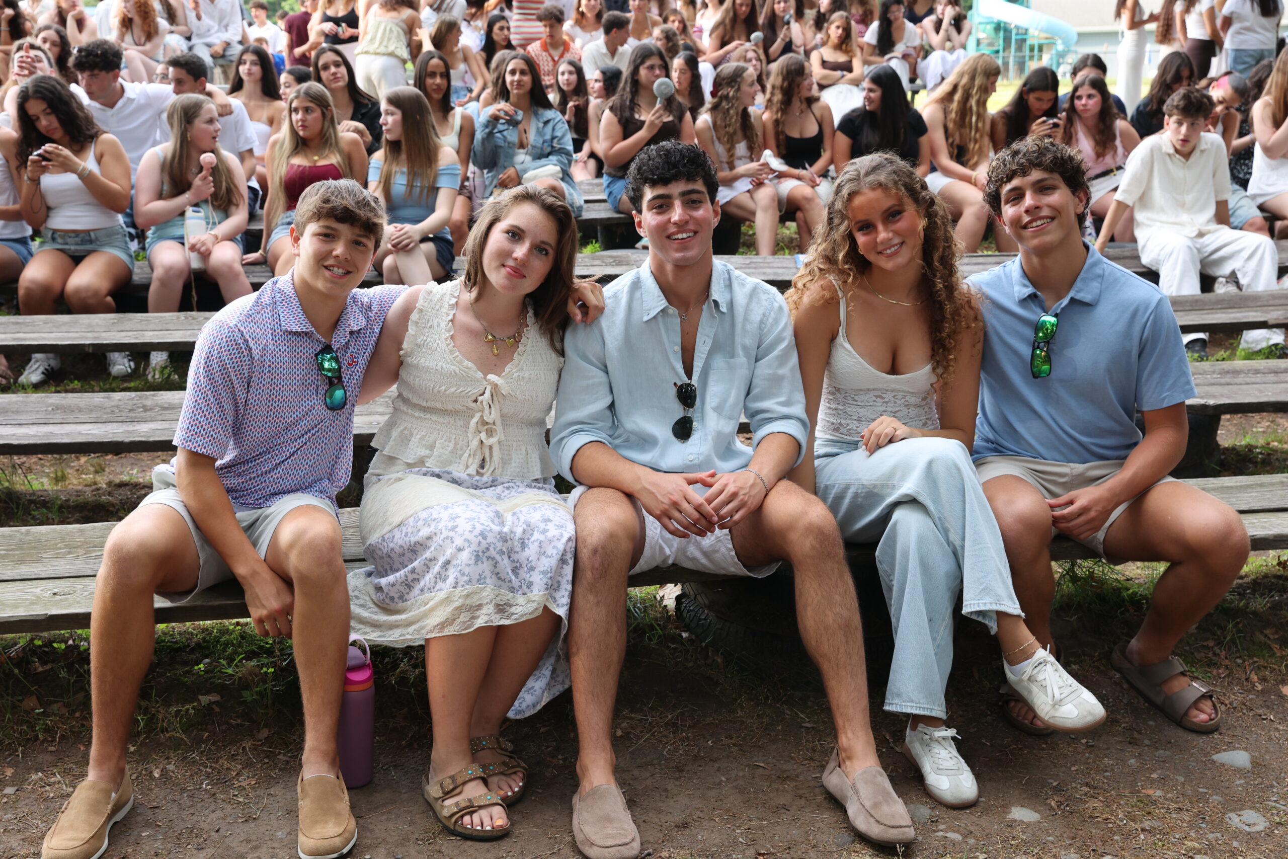 Group of teen friends sitting together, arms around each other